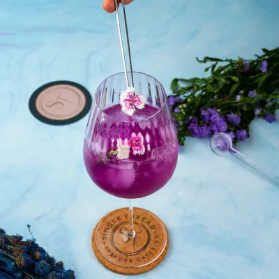This is 'The Butterfly Effect,' a stunning cocktail made with elderflower-infused gin, butterfly blue pea flower, and lime. Its vibrant purple hue and delicate floral garnish make it as beautiful as it is intoxicating.