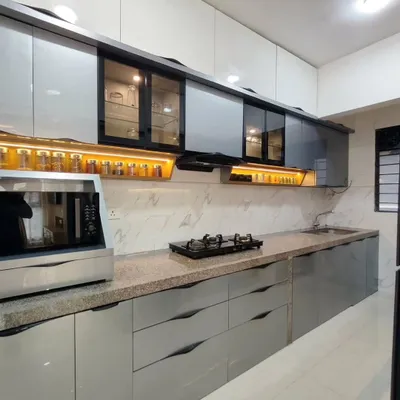 A sleek, straight-line kitchen with glossy grey cabinets and a granite countertop. The open spice rack with warm backlighting is a practical and beautiful feature, keeping essentials within easy reach.