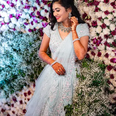 A fairytale moment for this beauty in her shimmering lehenga. Set against a wall of flowers, her soft glam makeup with a bright smile makes for a perfect reception photo.