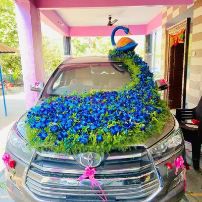 This is my signature peacock themed wedding car decoration on a Toyota Innova. The design features a beautiful peacock figure with a long, flowing tail of blue orchids and greenery covering the bonnet, making it a true showstopper.
