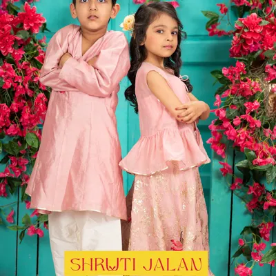 This pastel pink sibling set is one of my most popular designs for Rakhi and family photoshoots. The boy's simple angrakha style kurta perfectly complements the girl's peplum top and printed lehenga skirt, creating a look of effortless charm.