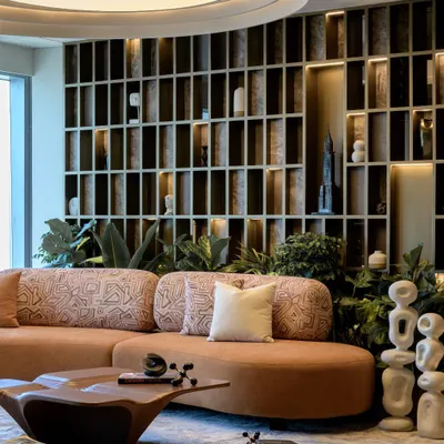 A wide view of the Midas Lounge, showing the harmony between the custom jacquard sofa, the backlit grid wall, and the abundant greenery. This space is designed for conversation and connection.