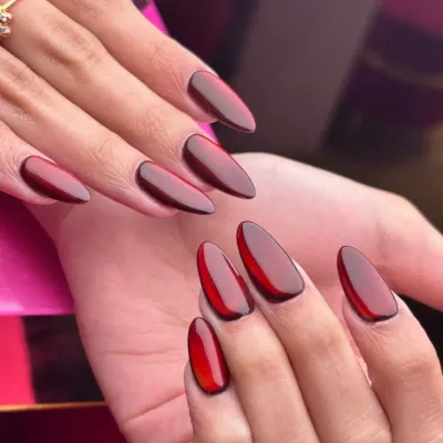 A bold and trendy look featuring deep red "jelly" nails. This translucent, glossy finish on almond-shaped extensions is a modern style that makes a vibrant and fashionable statement.