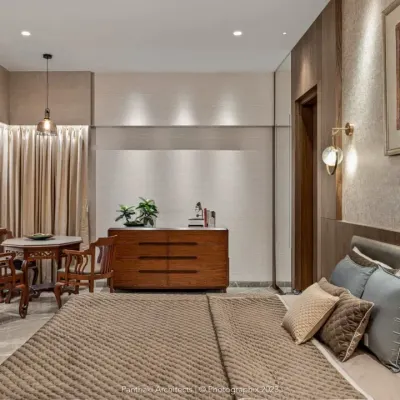 This master bedroom is designed as a refined retreat. It features a comfortable bed with an upholstered headboard, a separate seating area by the window, and custom-built wooden furniture, all working together to create a space of quiet luxury.