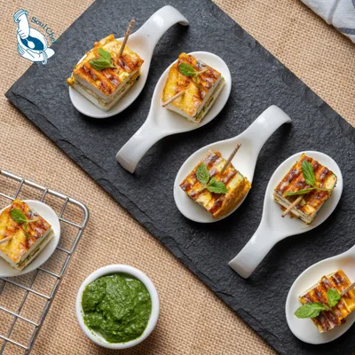 These Rozali Stuffed Paneer Sandwiches are a unique twist on a classic. Layers of paneer and flavorful stuffing are grilled and served in elegant bite-sized portions on ceramic spoons, making them a perfect mess-free option for any corporate gathering.