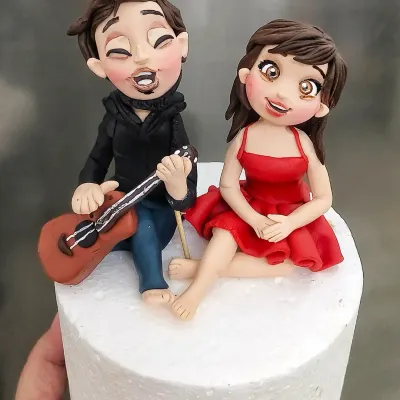 A close-up of the custom couple figurines for the beach-themed story cake. I love capturing expressions, like the joy on his face as he sings and plays the guitar. These toppers are the heart of the cake's narrative.