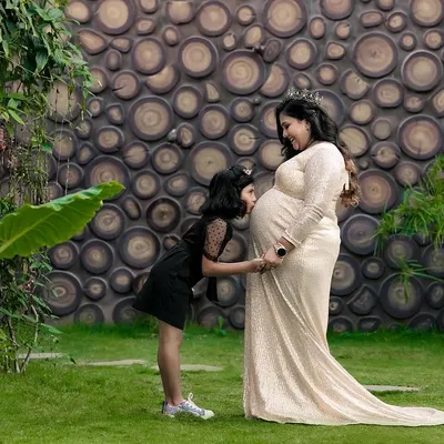 A big sister whispers secrets to her sibling on the way. This outdoor maternity photo captures the beautiful bond between a mother, her daughter, and the new life they are waiting for.
