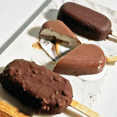 Beat the heat with our artisanal ice cream bars, made with the finest ingredients. This selection shows our classic chocolate, almond-coated, and caramel-filled bars.