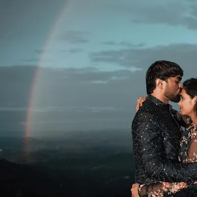 A romantic moment from a couple's photoshoot. The coordinated black embroidered outfits look stunning against the dramatic sky, creating a truly cinematic memory.