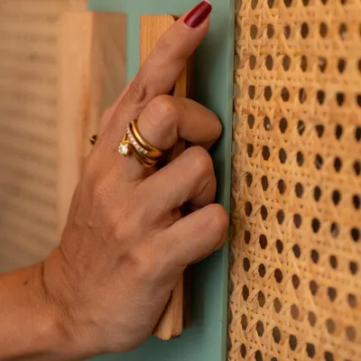 I believe in using materials that are both beautiful and sustainable. This close-up shows a custom handle on a rattan-paneled cabinet, a material I love for its natural texture, durability, and eco-friendly properties.