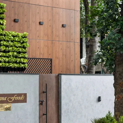The entrance to the Meghana Foods Corporate office, nestled in a tree-lined avenue in Koramangala. The design features a modern facade with a vertical garden, creating an inviting yet professional statement that stands out in a busy commercial hub.