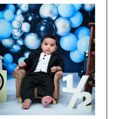 This little boy is celebrating his half-birthday in style. The '1/2' prop clearly marks the occasion, and his formal outfit makes for a dapper and adorable milestone portrait.