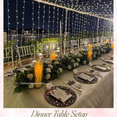 This is my signature dinner setup. A canopy of warm fairy lights creates a glowing tunnel over a beautifully styled long table, perfect for a special birthday or anniversary dinner.