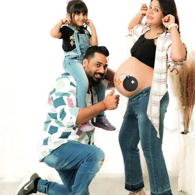 A fun and dynamic family maternity photo! Having the older sibling on dad's shoulders while mom shows off the bump creates a lively and joyful scene.