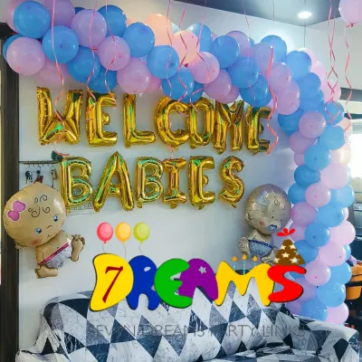 For a sweet and simple celebration at home, I offer welcome home decorations. This setup for twins features "WELCOME BABIES" foil balloons, cute baby-shaped foils, and a pink and blue balloon arch over the family sofa.