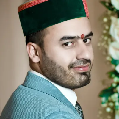 A classic headshot of a groom in a bright blue suit and Himachali cap. This over-the-shoulder pose is confident and engaging, perfect for a groom's portrait.