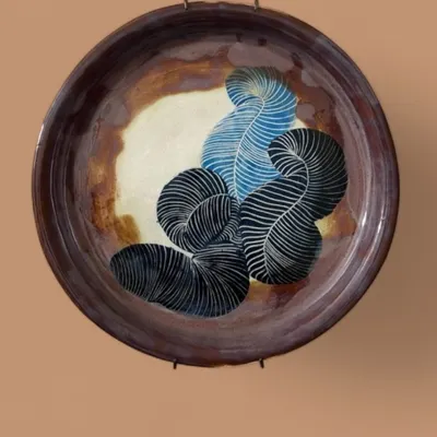 Titled 'Fleeting Oasis', this large sgraffito wall plate features abstract, feather-like forms. It’s a piece of ceramic art that plays with pattern and earthy tones, designed to be a contemplative focal point in any room.