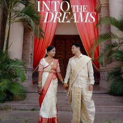 A grand portrait of the couple in traditional South Indian wedding attire, standing before a magnificent entrance. This shot, titled "Into the Dreams," captures the beginning of their new life together.