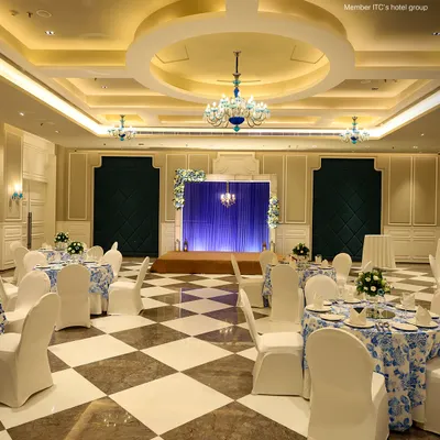 This is my premier banquet hall, elegantly decorated for a grand celebration. The striking blue and white floral tablecloths, combined with crystal chandeliers and a polished marble floor, create a sophisticated atmosphere for weddings and formal receptions.