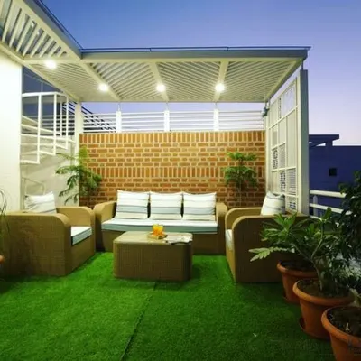 This terrace was designed as a complete outdoor living room. I installed a no-maintenance artificial lawn and added comfortable wicker furniture under a protective pergola, creating a perfect space for family time.