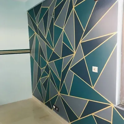 A completed geometric feature wall combining deep teals and cool greys with striking gold accents. This custom wall painting transforms the room with a bold, contemporary feel.
