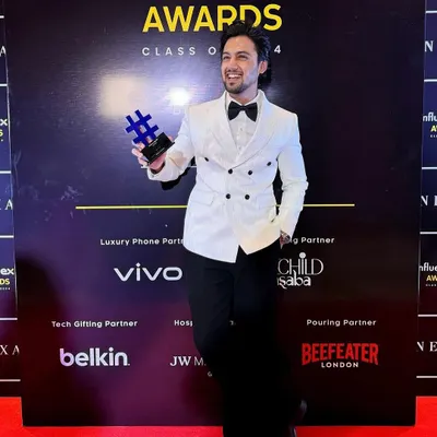 Our client Mohak Narang accepting the Best Influencer Award in a custom Levelline tuxedo. The white textured double-breasted blazer and black Japanese trousers create a sharp, award-winning look.