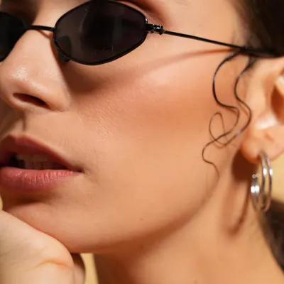 A clean and modern beauty shot focusing on the chic sunglasses and subtle wet-look hair styling. This type of close-up is perfect for accessory brands or minimalist beauty campaigns.