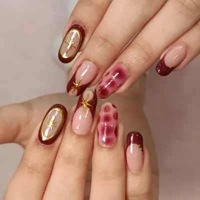 A complete view of this gorgeous set. The design combines deep maroon French tips, a unique blooming gel accent nail, and delicate gold star charms for a celestial-inspired look.