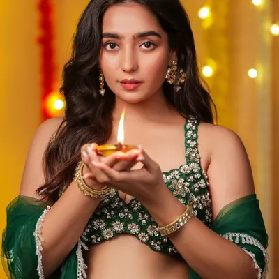 A radiant Diwali-themed portrait. The model holds a lit diya, and the warm glow illuminates her face, perfectly capturing the spirit of the festival of lights.