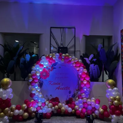 A circular ring backdrop is a popular and versatile choice for many events like engagements or anniversaries. Here, I have decorated it with a dense garland of pink, white, and gold balloons and soft lighting to highlight the couple's names.