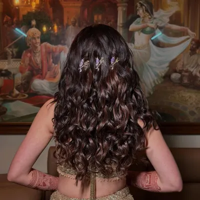 The final look for Ria's sangeet. These voluminous curls have incredible movement and are accented with delicate purple bird clips, adding a touch of whimsy to a glamorous golden lehenga.