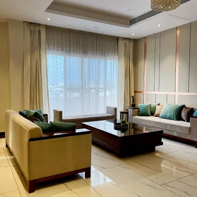 A modern living room featuring a neutral color palette with elegant rose gold metal inlays on the wall paneling. The design creates a sophisticated yet comfortable atmosphere, perfect for contemporary urban living.