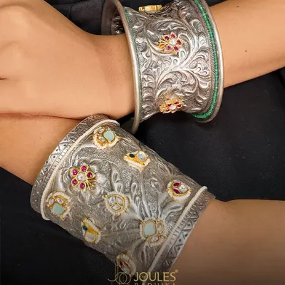 Oxidized beauty, handcrafted to perfection. This image showcases two of our statement kadas, featuring intricate floral carvings on oxidized silver, one accented with colorful stones.