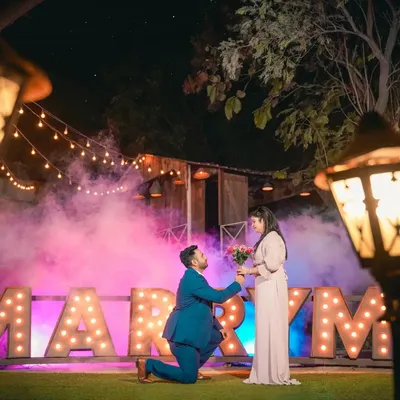 A beautiful proposal moment captured with our 'MARRY ME' marquee letters, enhanced by dramatic pink and purple smoke for a truly cinematic feel. This is a perfect example of a pre-wedding proposal shoot.