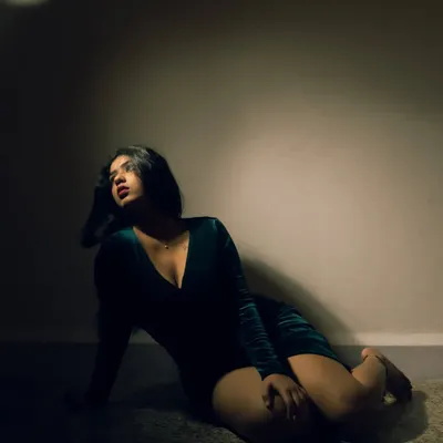 A dramatic portrait using a single, focused light source to create a spotlight effect. The deep shadows and rich color grading give this shot a cinematic, mysterious quality.
