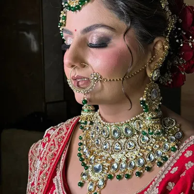 A side profile of a traditional bridal look, highlighting the contour, blush placement, and how the hairstyle with a red rose bun complements the entire ensemble.