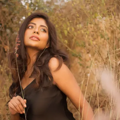 A portrait taken in a field of tall, dry grass during the golden hour. The warm, diffused light creates a soft, dreamy atmosphere, perfect for a natural and romantic lifestyle shoot.