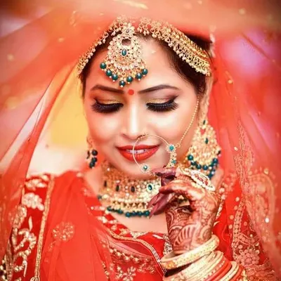 A classic Indian bridal portrait. This look features defined, kohl-rimmed eyes with gold shimmer, a flawless matte base, and traditional red lipstick, perfect for a wedding ceremony.