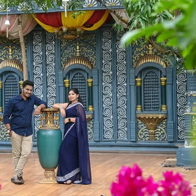 This couple chose a South Indian village theme for their pre-wedding shoot. The intricate blue wall and traditional elements create a stunning backdrop.