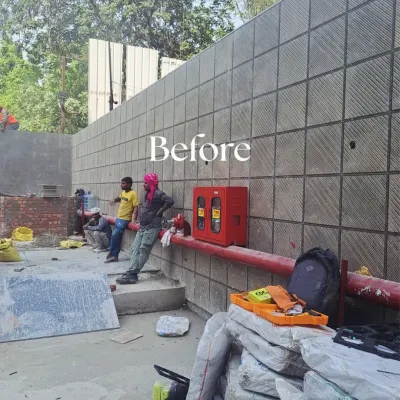 Before: A large, plain stone-tiled wall at a construction site, presenting a blank canvas for a major green transformation.