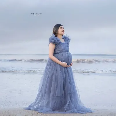 A little piece of heaven by the sea. This mama-to-be looks absolutely ethereal in a dusty blue tulle gown, standing by the calm ocean. It's a perfect, serene beach maternity portrait.