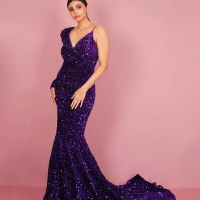 A full-length studio portrait of Daisy Shah. The simple pink background makes the vibrant purple of the sequin gown pop, creating a bold and memorable image for promotions.