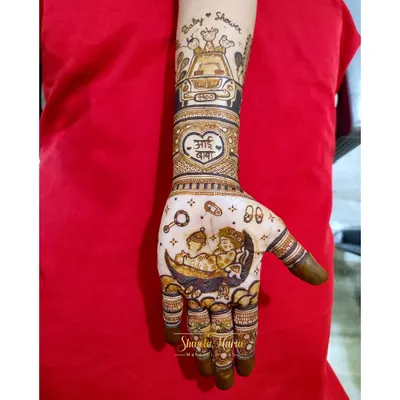 A close-up of a custom baby shower mehendi. This design features two babies sleeping on a crescent moon, surrounded by tiny footprints and rattles, with a special 'Aai Baba' heart motif on the wrist.