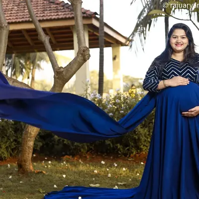 A flowing gown adds such a magical element to an outdoor maternity shoot. Here, the deep blue fabric contrasts beautifully with the natural greenery, creating an elegant and striking portrait of the mom-to-be.