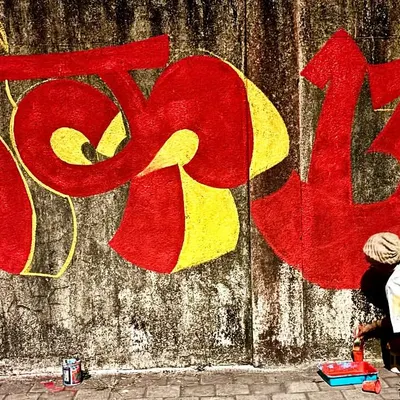 Aarela hai apun! Me painting my tag 'Vrek13' in bold Devanagari script on a weathered wall in my hometown, Bombay. This is street art with local flavor.