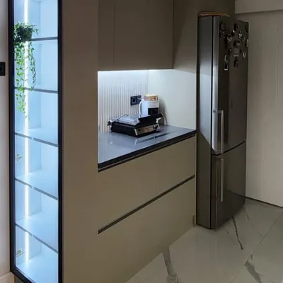 A tall, floor-to-ceiling crockery unit with a black frame and glass doors. The internal LED lighting beautifully illuminates the glassware and decor inside, turning everyday items into a stunning display.