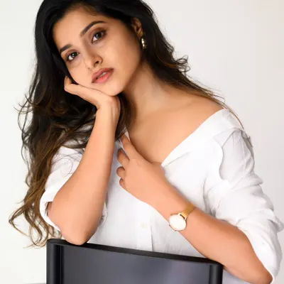 A classic, clean studio portrait with a white shirt and jeans. The bright, even lighting and simple background put all the focus on the subject's natural beauty and expression.