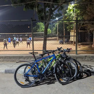 Our cycles parked by a volleyball court in AECS Layout. Even as others play, we find our own game on the city's empty streets.