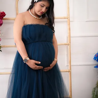 A quiet moment of reflection. This portrait captures the serene beauty of pregnancy, using soft lighting and a classic pose to highlight the mother's gentle connection with her baby.