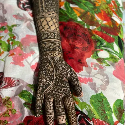 A complete bridal henna design from the fingertips to the forearm. This style features multiple bands with different patterns, including jaal netting, florals, and traditional leaf motifs.